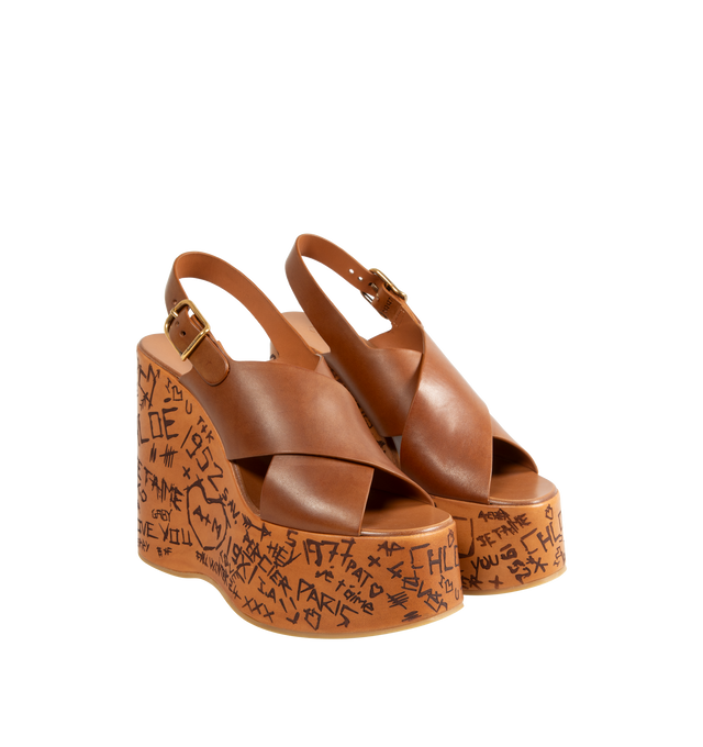 Image 2 of 4 - BROWN - CHLOE Maxime Wedges featuring criss-cross straps in semi-shiny cowhide with a wood-effect platform structure and Chlo-engraved buckle. 5.1" heel. Upper: semi-shiny cowhide. Inner sole: calfskin. Main lining: calfskin. Secondary lining: cowhide. Sole: thermoplastic polyurethane. 