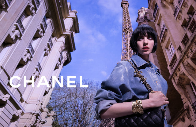 Woman in Paris wearing denim shirt and carrying black quilted chain bag by CHANEL