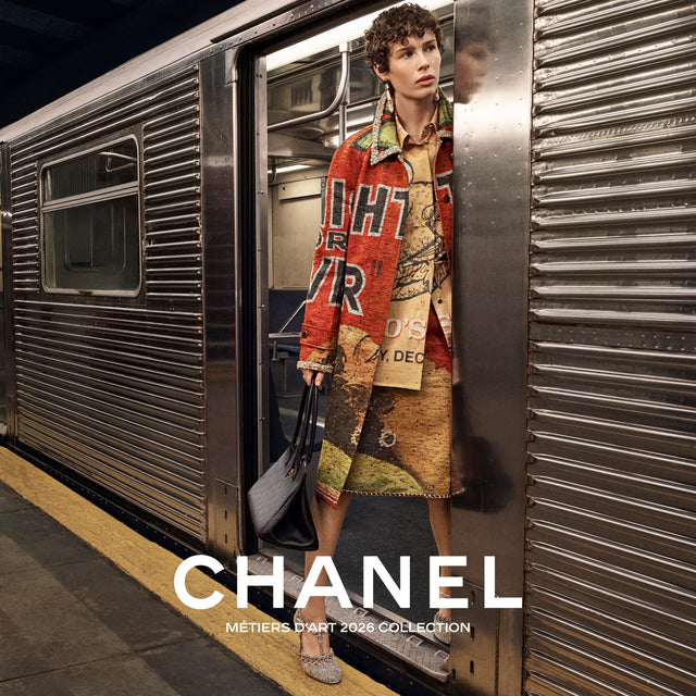 Person exiting a subway train wearing a Chanel outfit with the brand name displayed. 