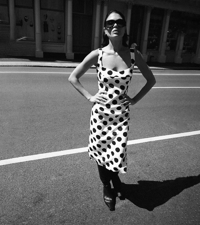 Woman wearing white and black polka dot sleeveless dress by Marni, available online.