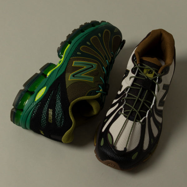 A pair of New Balance 1890 running shoes in a green, black, and white colorway, displayed on a neutral gray background.