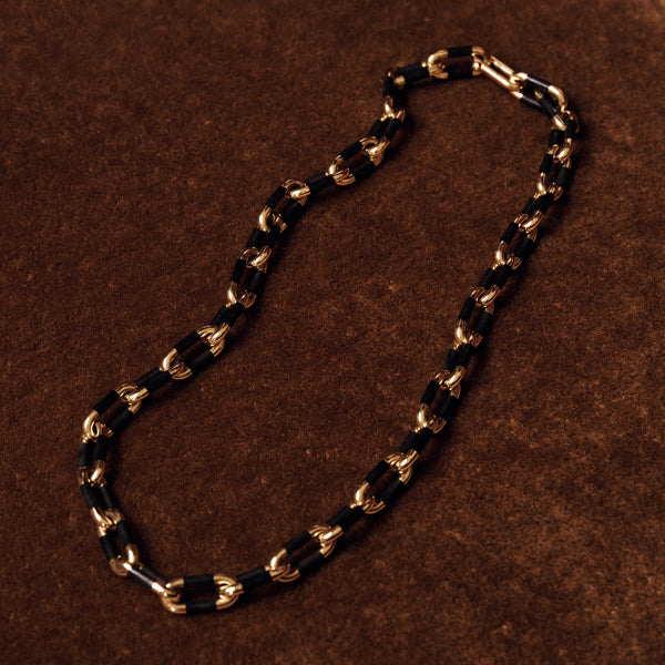 Sidney Garber gold and black chain necklace with alternating polished gold links and black rectangular links, displayed on a textured brown background.