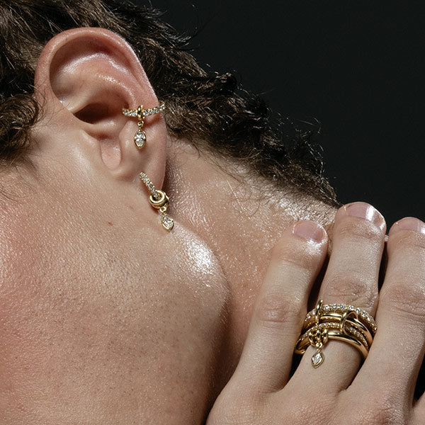 Model wearing gold and diamond drop earrings and gold and diamond linked rings by Spinelli Kilcllin