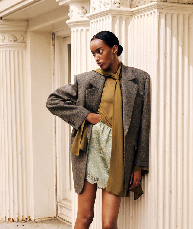 Model wearing Saint Laurent wool blazer, sage brocade mini skirt and olive green tie neck blouse 