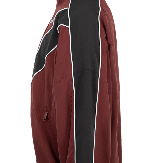 Image 3 of 3 - RED - Willy Chavarria Bad Boy Track Jacket is crafted from nylon and features a sleek, true-to-size silhouette defined by bold chevron paneling and contrast piping. Designed with a stand collar, front zip closure, two zippered pockets, stacked script logo detailing, and elasticized cuffs and hem. Main Material: 100% Nylon. Lining: Polyester. 