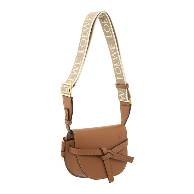Image 2 of 2 - BROWN - LOEWE Mini Gate Dual bag with a saddle-stitched knotted leather strap and a side-latched metal pin that gives the bag its name. This mini version is crafted in soft calfskin and features a removable shoulder strap in calfskin and jacquard with a repeat LOEWE pattern. Shoulder, crossbody, sling or belt carry. Front flap pulls in under knotted belt for secure fastening.  Two internal slip pockets and suede lining. Embossed Anagram.featuring a shoulder strap. 100% Leather.  