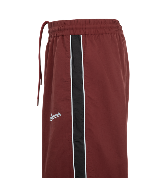 Image 3 of 3 - RED - Willy Chavarria Bad Boy Track Pant is crafted from lightweight nylon and features a relaxed athletic silhouette with an elasticated waistband and cuffs. Designed with a concealed drawstring waist, two seam pockets, embroidered logo detailing, and contrast piping along the outseams, the pant delivers the brand's bold sportswear-inspired aesthetic. Main Material: 100% Nylon.  