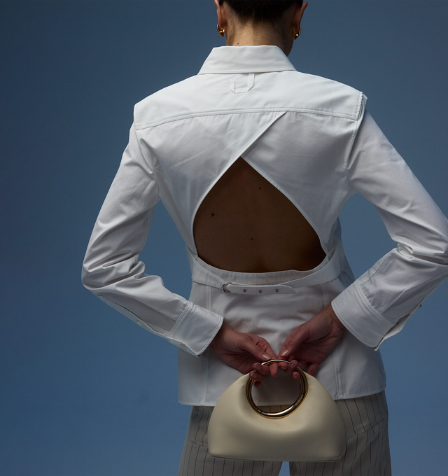 Image 3 of 3 - WHITE - JACQUEMUS Open Back Shirt featuring fitted shape, cotton poplin, pointed collar, asymmetric J shaped chest pocket, buttoned cuffs, J locker loop, back yoke, triangular open back, integrated buckled belt and metal ring and studs. 100% cotton. Made in Bulgaria. 