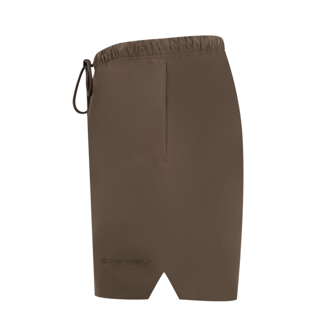 Image 3 of 3 - BROWN - FEAR OF GOD ESSENTIALS Active Trace Relaxed Short featuring a perforated lining for enhanced breathability, a voluminous, elongated silhouette, 3M Embroidered Essentials Active Trace logo divided across both legs, Essentials signature label is positioned at the center front, side pockets, leg slits and an encased elastic waistband with drawstrings. 100% polyester. 