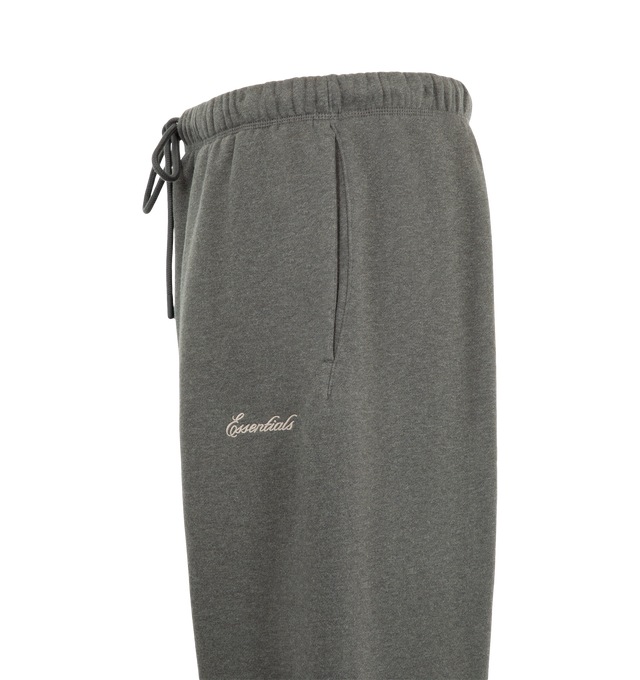 Image 3 of 3 - GREY - Fear of God ESSENTIALS Men's Signature Flare Sweatpant is crafted from heavyweight 380 GSM cotton-blend fleece and features a relaxed-fit silhouette that extends into a flared leg. Designed with the Essentials signature logo embroidered at the leg, this elevated loungewear style is finished with an encased elastic waistband, elongated drawcords, side-seam pockets, and a signature Essentials label at the center front. Main Material: 80% Cotton, 20% Polyester, 380 GSM.  