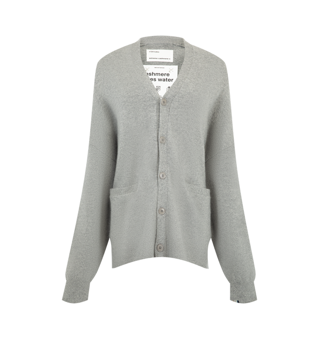 Image 1 of 2 - GREY - Extreme Cashmere Women's N24 Tokio Cardigan Sweater is crafted from a premium cashmere blend and features a relaxed silhouette with dropped shoulders, two front patch pockets, and a unique side button that allows for adjustable styling. This designer cashmere cardigan combines exceptional softness with versatile functionality, while durable natural corozo buttons add a refined finishing touch. Main Material: 88% Cashmere, 10% Nylon, 2% Elastane. 