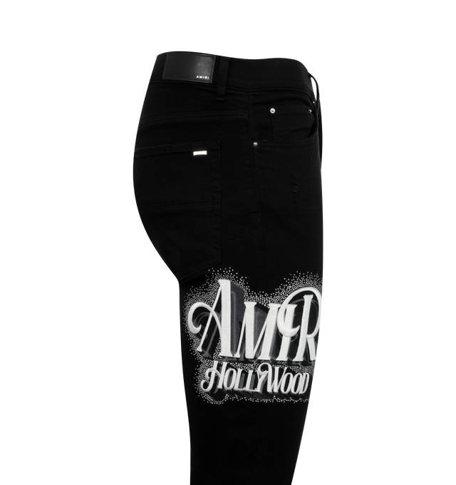 Image 3 of 3 - BLACK - AMIRI Crystal Logo Jeans featuring logo lettering with crystal embellishment at right thigh, regular rise, five-pocket style, full length, fitted through skinny legs and button zip closure. 100% cotton. 