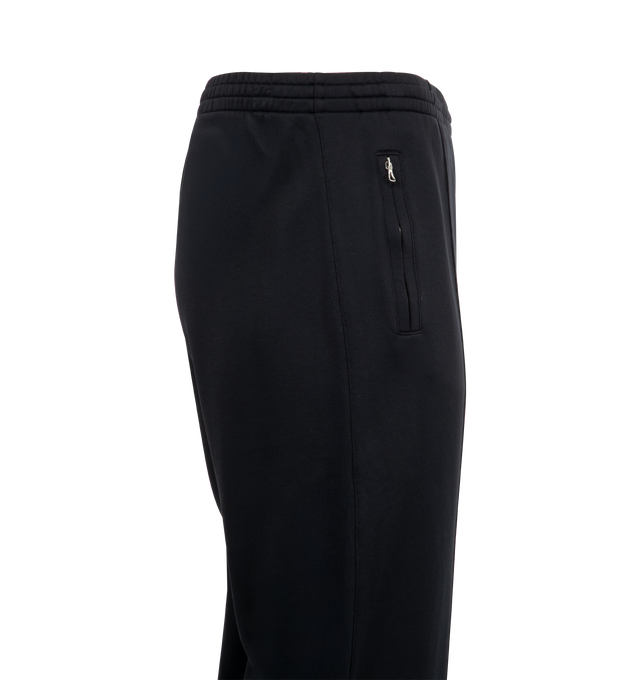 Image 3 of 3 - BLACK - OUR LEGACY Track Pants featuring soft fleece jersey, drawstring waist, two side pockets, stitched crease, vented side seam with zip closure and relaxed, wide legged fit. 55% polyamide, 45% cotton. 