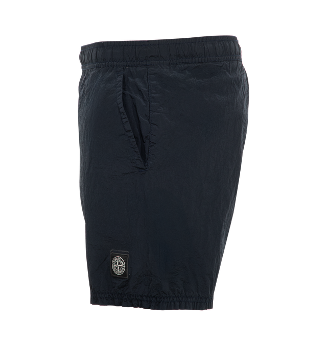 Image 3 of 3 - NAVY - Stone Island regular-fit mid-length swim trunks made from a new responsible iridescent Nylon Metal fabric with ECONYL regenerated yarns, featuring Velcro pockets and inner mesh lining. Garment dyed with double-dye procedure. External Fabric: 100% Polyamide / Nylon. Lining: 100% Polyamide / Nylon. Made in Indonesia. 