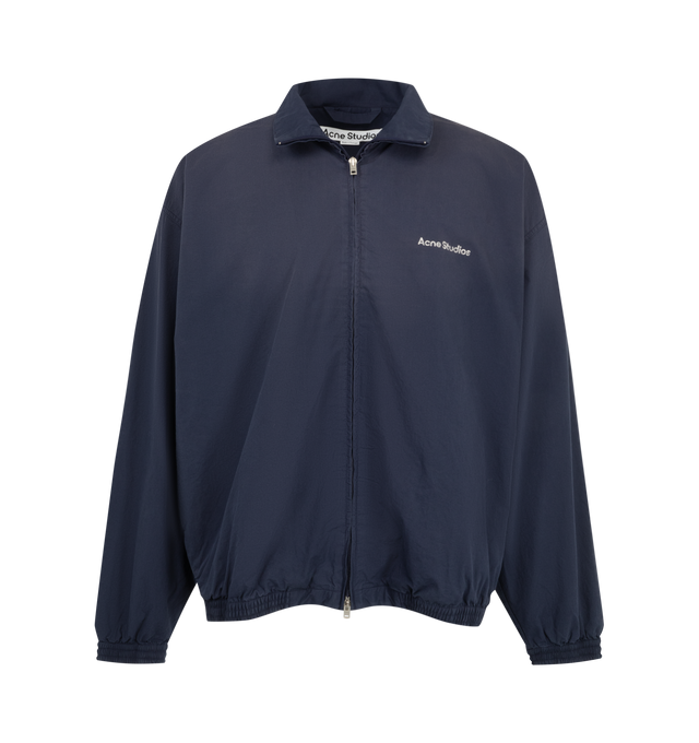 Image 1 of 3 - NAVY - Acne Studios Mens Technical Jacket is crafted from cotton poplin. Features a relaxed fit, high collar, two-way zip closure, side seam zip pockets, elasticized cuffs and hem, mesh lining, and Acne Studios 1996 logo stamp artwork. Main Material: 100% Cotton; Lining: 82% Nylon, 18% Elastane. Made with organically grown cotton and recycled nylon lining. Made in Portugal. 