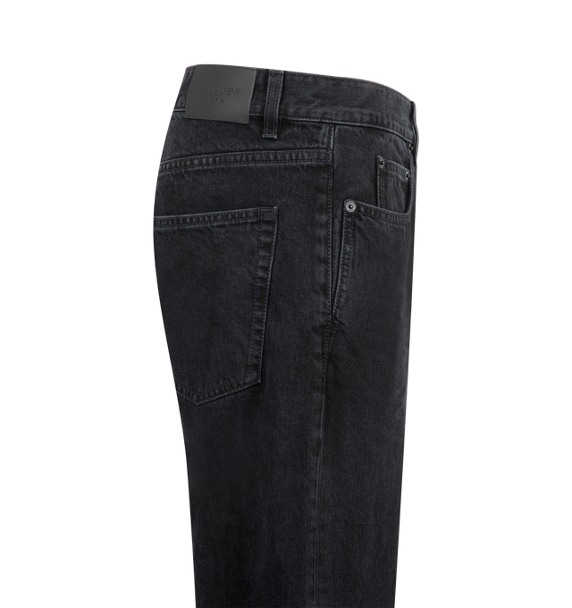 Image 3 of 3 - BLACK - Saint Laurent Men's Relax Tapered Jeans are crafted from pure cotton denim with a washed black finish that creates a naturally worn-in appearance and added depth of color. Designed with a relaxed fit that tapers toward the hem, these designer jeans feature classic five-pocket construction, belt loops, a front button closure, and a Saint Laurent Paris embossed leather logo patch at the back waistband. Main Material: 100% Cotton. Fit: Relaxed Tapered. Closure: Button Front. Pockets: Fiv 