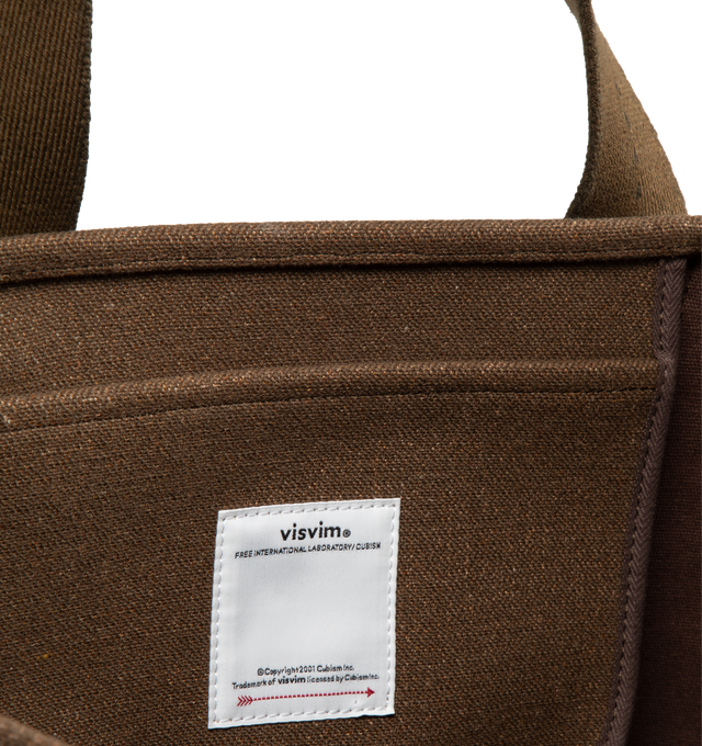 Image 3 of 3 - BROWN - VISVIM Comber medium bag with canvas exterior and lining featuring one main compartment with single interior flat pocket. Measures approx 19.5" W x 14.5" H x 5.5" D. Shoulder strap with a 9.5" drop.  62% wool, 38% linen. Lining: 100% cotton. 