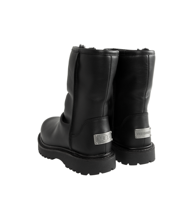 Image 3 of 4 - BLACK - UGG x Willy Chavarria Relaxed Boot is crafted from leather and features a mid-calf silhouette inspired by classic motorcycle boots. Designed as a slouchier interpretation of the biker boot, it is detailed with custom chrome logo hardware, a draped black leather upper, and a soft sheepskin-lined interior that combines rugged styling with signature comfort. Main Material: Leather. Lining: Sheepskin. Unisex style in men's sizes. 