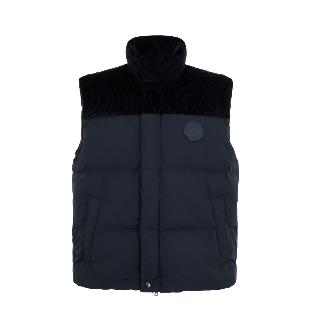 Image 1 of 3 - NAVY - Canada Goose Men's Sterling Corduroy Puffer Vest is crafted from signature Recycled Organic Arctic Tech with breathable Italian cotton corduroy at the shoulders and collar. Designed for temperatures from 41F to 23F, it features a concealed snap placket over a two-way zipper, an adjustable drawcord hem, two exterior snap-welt pockets, and two interior pockets. Main Material: 100% Cotton. Fill: 90% Down, 10% Feathers.  
