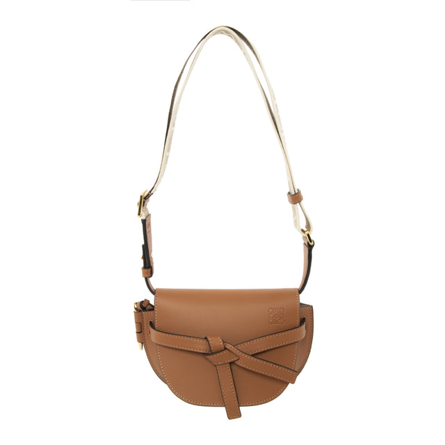 Image 1 of 2 - BROWN - LOEWE Mini Gate Dual bag with a saddle-stitched knotted leather strap and a side-latched metal pin that gives the bag its name. This mini version is crafted in soft calfskin and features a removable shoulder strap in calfskin and jacquard with a repeat LOEWE pattern. Shoulder, crossbody, sling or belt carry. Front flap pulls in under knotted belt for secure fastening.  Two internal slip pockets and suede lining. Embossed Anagram.featuring a shoulder strap. 100% Leather.  