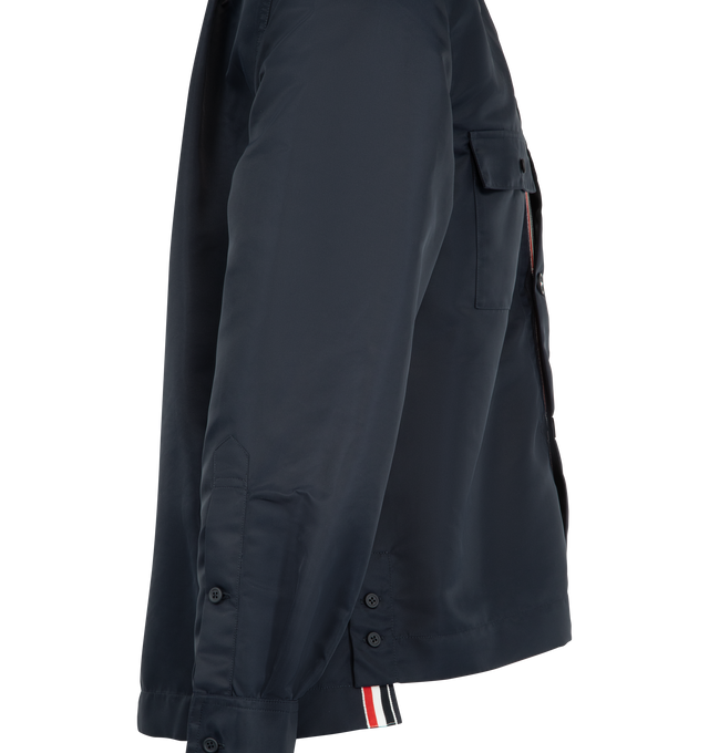 Image 3 of 3 - BLUE - Thom Browne Mens Tech Twill Shirt is crafted from lightweight technical twill. Features a button-front closure with signature RWB detailing, club collar with buttoned tab closure, buttoned flap chest pockets, buttoned cuffs, reinforced pleated back yoke with locker loop, buttoned side vents with internal RWB grosgrain trim, stepped hem, name tag appliqu, and signature striped grosgrain loop tab. Main Material: 100% Polyamide. Made in Italy. 