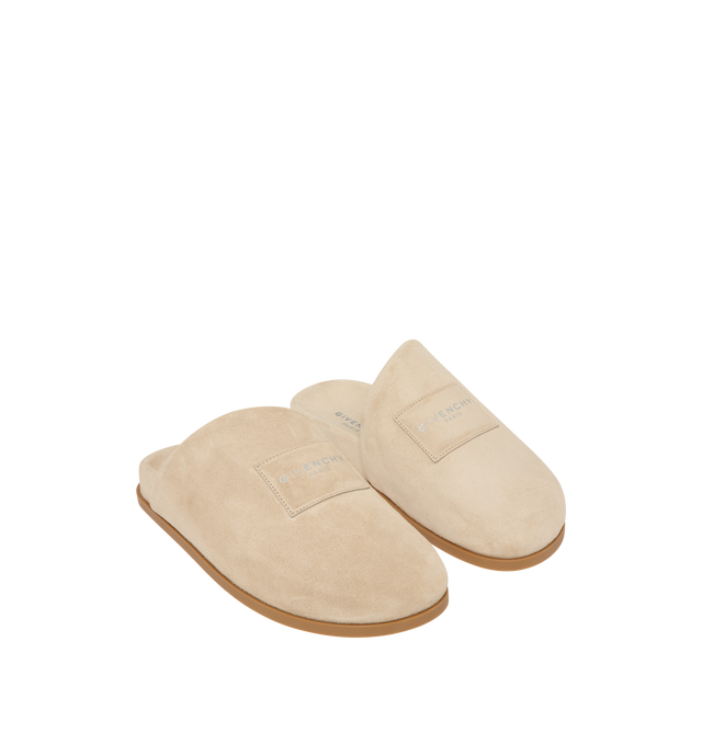 Image 2 of 5 - NEUTRAL - Givenchy Puffy Mules in Suede are crafted from supple calfskin suede and feature the house's signature Puffy silhouette with an asymmetric, slip-on design. Designed with a tonal padded label accented by a silvery Givenchy Paris logo, a branded leather insole, and a raised Givenchy signature beneath the sole, the mules combine comfort with a refined contemporary aesthetic. Main Material: 100% Calfskin Leather. Lining: 100% Calfskin Leather. Made in Italy. 