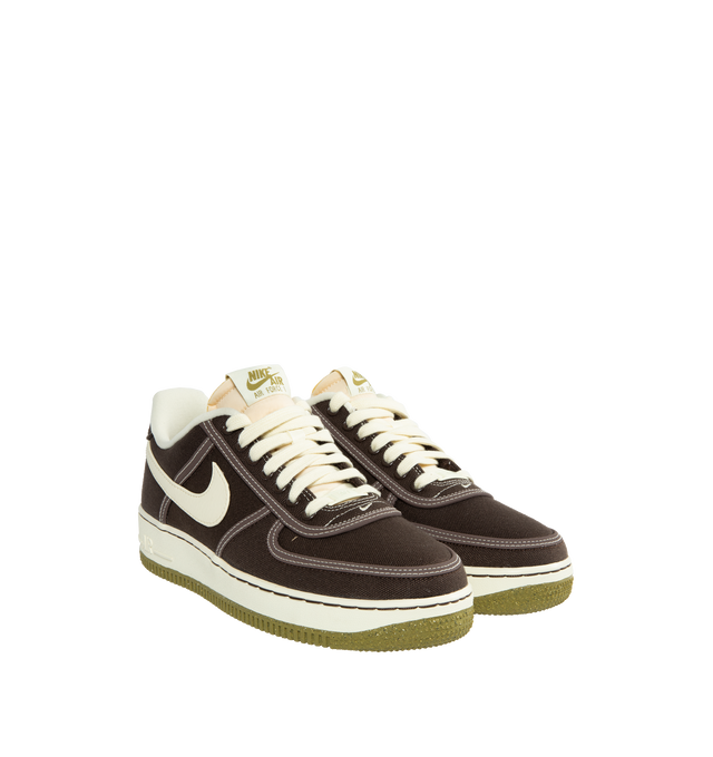 Image 2 of 5 - BROWN - NIKE AIR FORCE 1 '07 PREMIUM Baroque Brown highlights canvas materials reversed to reveal raised leather trims, in a deep chocolate brown color. Accented stitching in a lively Sail shade extends to the midsole, laces, profile swoosh, inner lining, and exposed foam within the tongue. Additionally, olive-cured details highlight the insoles and tongue tabs. 