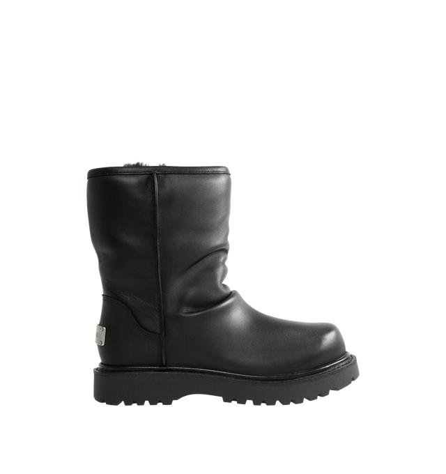 Image 1 of 4 - BLACK - UGG x Willy Chavarria Relaxed Boot is crafted from leather and features a mid-calf silhouette inspired by classic motorcycle boots. Designed as a slouchier interpretation of the biker boot, it is detailed with custom chrome logo hardware, a draped black leather upper, and a soft sheepskin-lined interior that combines rugged styling with signature comfort. Main Material: Leather. Lining: Sheepskin. Unisex style in men's sizes. 