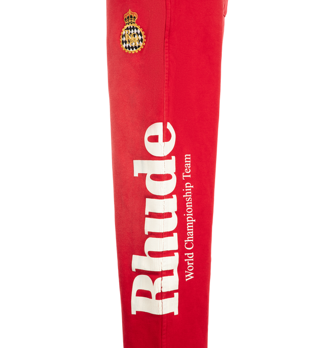 Image 3 of 4 - RED - Rhude Desert Racing Script Cuffed Sweatpant is crafted from cotton and features a relaxed silhouette with elasticated cuffs for a tapered fit. Designed with Desert Racing Script graphics, an elasticated waistband, and functional pocket detailing for everyday comfort. Main Material: 100% Cotton. Made in USA. 