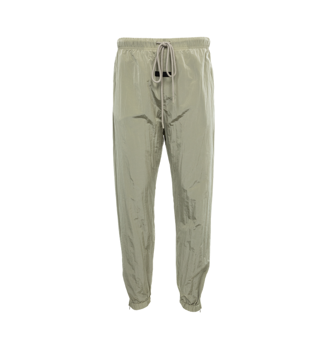 Image 1 of 4 - GREEN - FEAR OF GOD ESSENTIALS Crinkle Nylon Trackpants featuring an encased elastic waistband with elongated drawstrings, side seam pockets, an elastic hem with zipper adjustability at the ankle and a rubberized label at the center front. 100% nylon.  