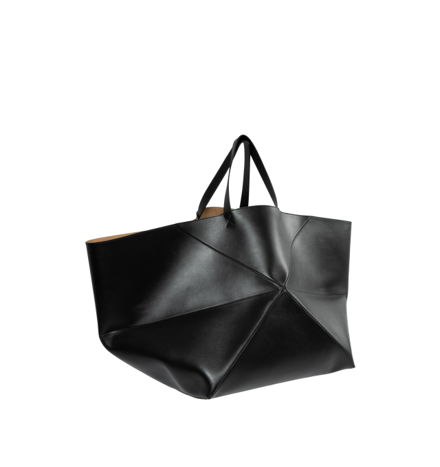 Image 2 of 3 - BLACK - XXL Puzzle Fold Tote in shiny calfskin takes the iconic bags signature geometric lines and reimagines them in graphic and architectural panels that allow the bag to fold completely flat, making it the perfect travel companion. Soft, lightweight and inventively crafted, it is finished with discreet LOEWE branding. This XXL version is crafted in shiny calfskin with gold embossed LOEWE and suede lining. Hand carry. 