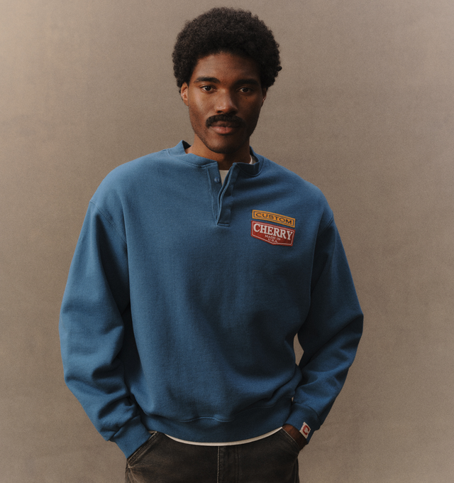 Image 5 of 7 - BLUE - Cherry LA Men's Patch Work Henley Crew is crafted from custom cotton fleece and features a boxy-fit silhouette with patchwork detailing at the chest and a concealed-button Henley placket. Designed for everyday comfort, this elevated sweatshirt is finished with hidden front buttons and a signature branded label at the cuff. Main Material: Custom Cotton Fleece. Made in Los Angeles, California. 