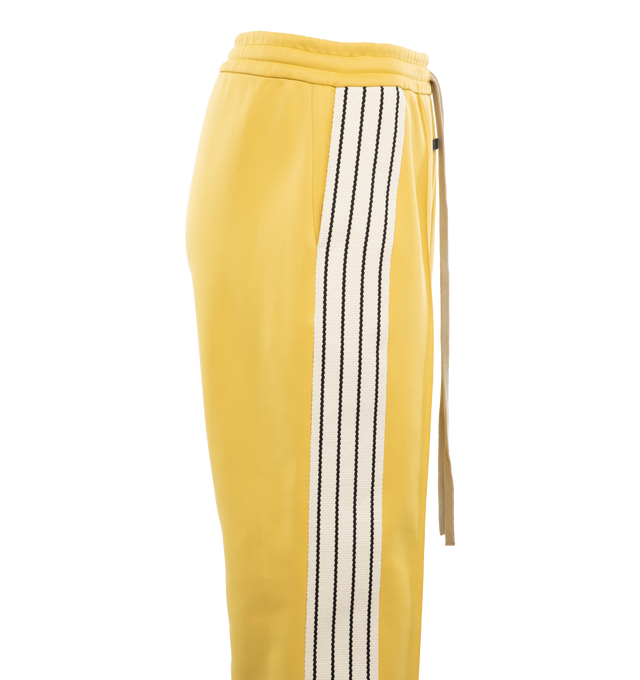 Image 3 of 4 - YELLOW - FEAR OF GOD Stripe Relaxed Sweatpant featuring a relaxed fit with a pintuck stitch to shape the leg and a sports-inspired canvas side stripe, pockets, encased elastic waistband, elongated drawstrings and Fear of God leather label at the center front. 60% nylon, 40% cotton. 