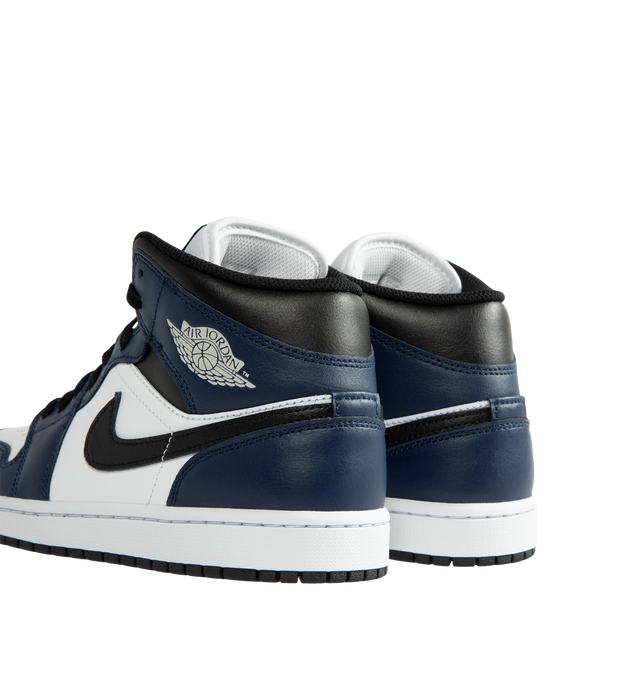 Image 3 of 5 - NAVY - Air Jordan 1 Mid Men's Shoes are crafted with a combination of leather, synthetic leather, and textile materials and feature the iconic mid-top silhouette inspired by the original Air Jordan 1. Designed with Nike Air cushioning, a foam midsole, and a durable rubber outsole with a pivot circle, this classic sneaker delivers lightweight comfort and everyday traction. Signature details include a stitched Swoosh logo, Wings logo at the collar, and Jumpman branding at the tongue. Main Mater 