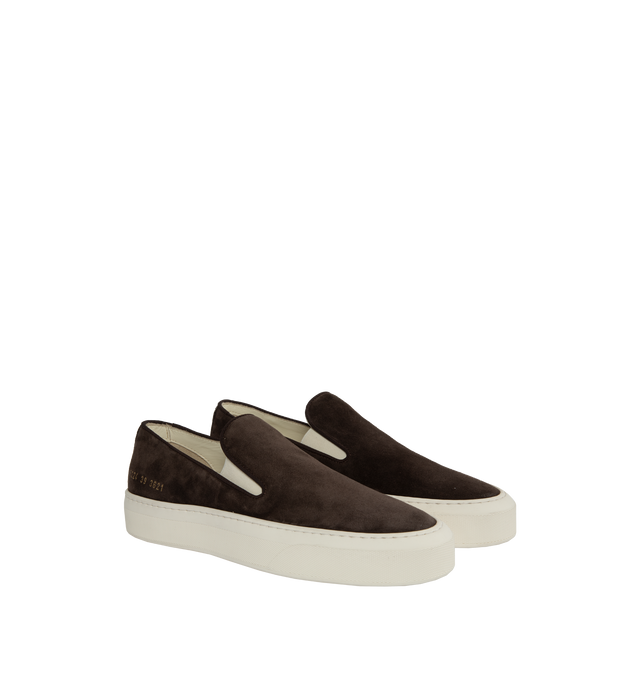 Image 2 of 5 - BROWN - Common Projects minimalist slip-on sneaker crafted from calf suede in a sleek, round-toe profile with thick rubber soles detailed at the heels with signature gold serial number stamp. Made in Italy. 