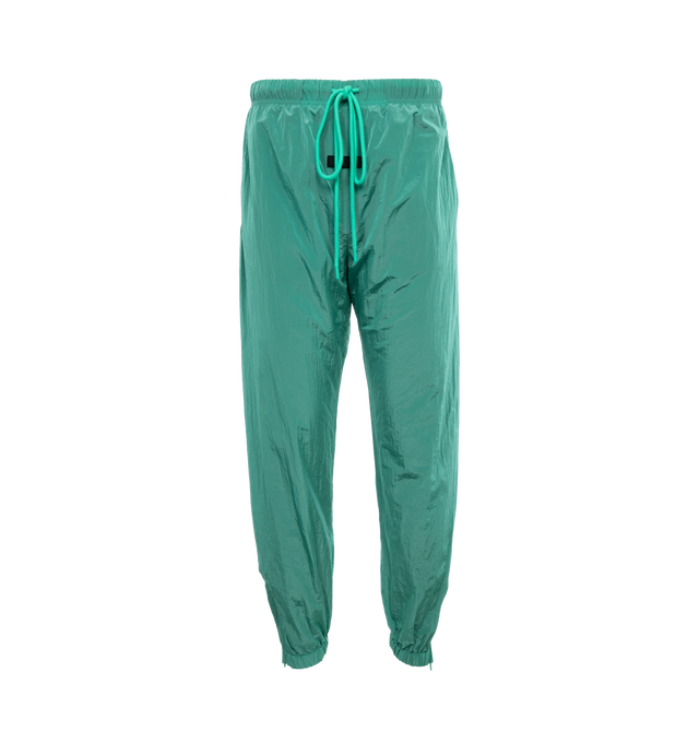 Image 1 of 4 - GREEN - FEAR OF GOD ESSENTIALS Crinkle Nylon Trackpants featuring an encased elastic waistband with elongated drawstrings, side seam pockets, an elastic hem with zipper adjustability at the ankle and a rubberized label at the center front. 100% nylon.  