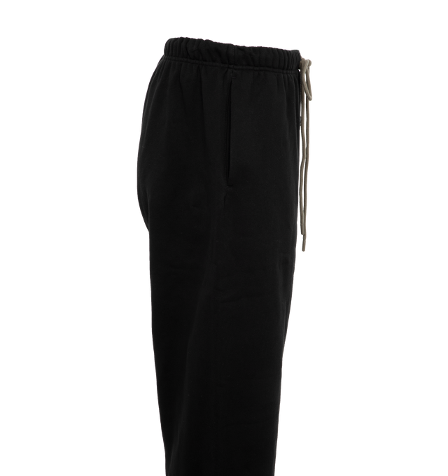 Image 3 of 4 - BLACK - Fear of God  Essentials lounge sweatpant made in core fleece and designed in a wide-leg fit for pronounced drape. Featuring rubberized label at the center front, encased elastic waistband with elongated drawstrings with rubberized tips and side seam pockets. 80% cotton, 20% polyester heavyweight fleece. 