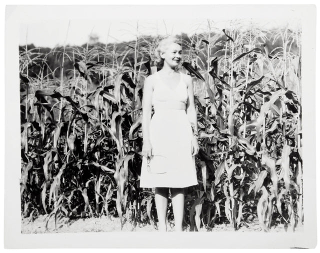 Black and white Hirshleifer family photo - a woman wearing a dress standing in a corn field