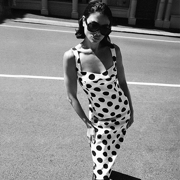 Woman wearing white and black polka dot sleeveless midi dress by Marni, available online.