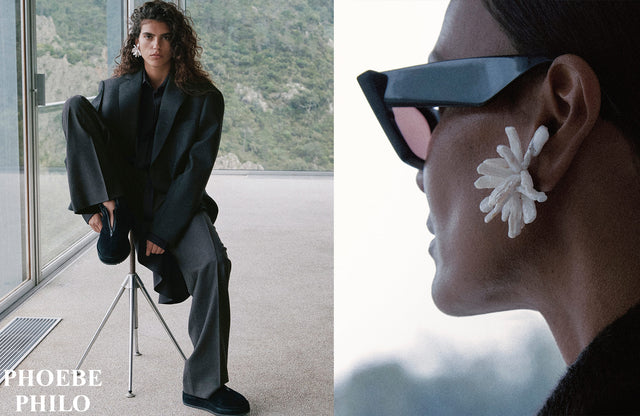 Person in a modern interior setting with a mountain view, wearing a black outfit and sunglasses by Phoebe Philo.